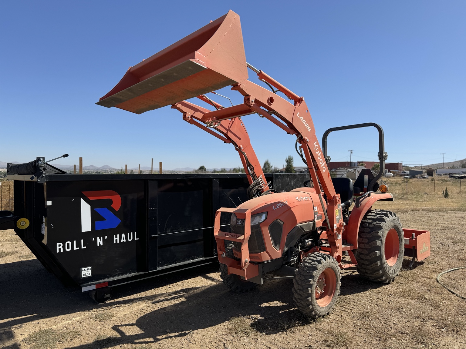 Roll N Haul Kubota tractor next to roll-off dumpster